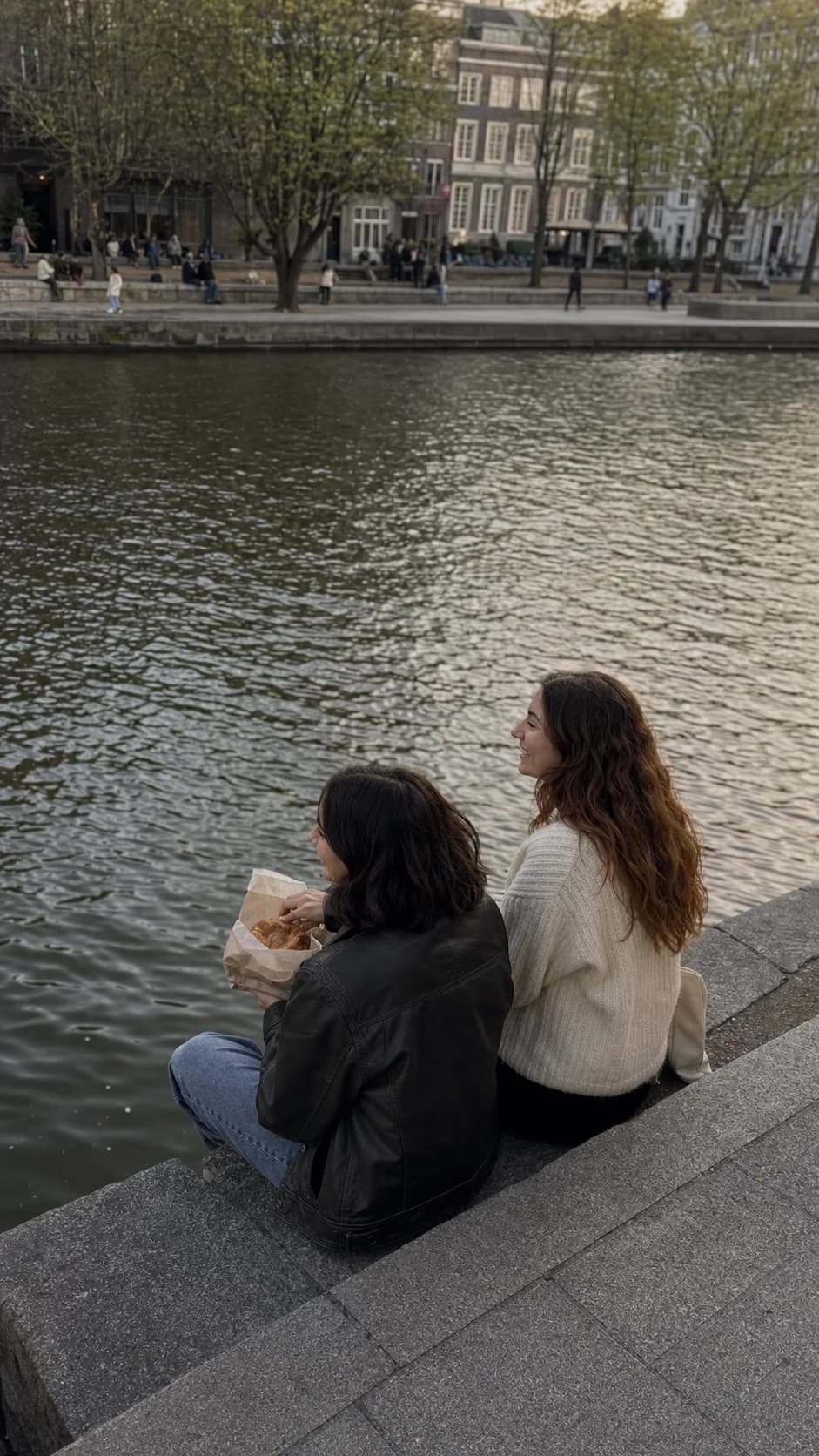 The friends sitting by a canal and sharing pastries