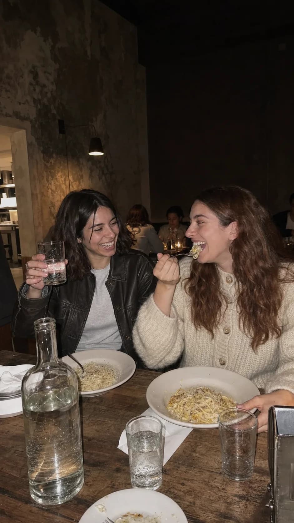 The friends laughing over dinner in a small restaurant